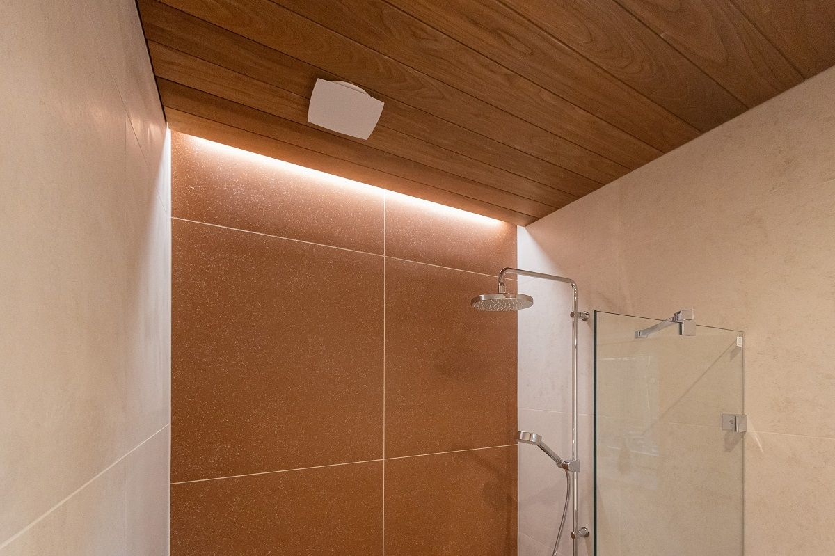 Accent lighting on the back wall of the shower with LED strip lighting brings beautiful light into a space in the groove of a paneled ceiling that has been left bare.